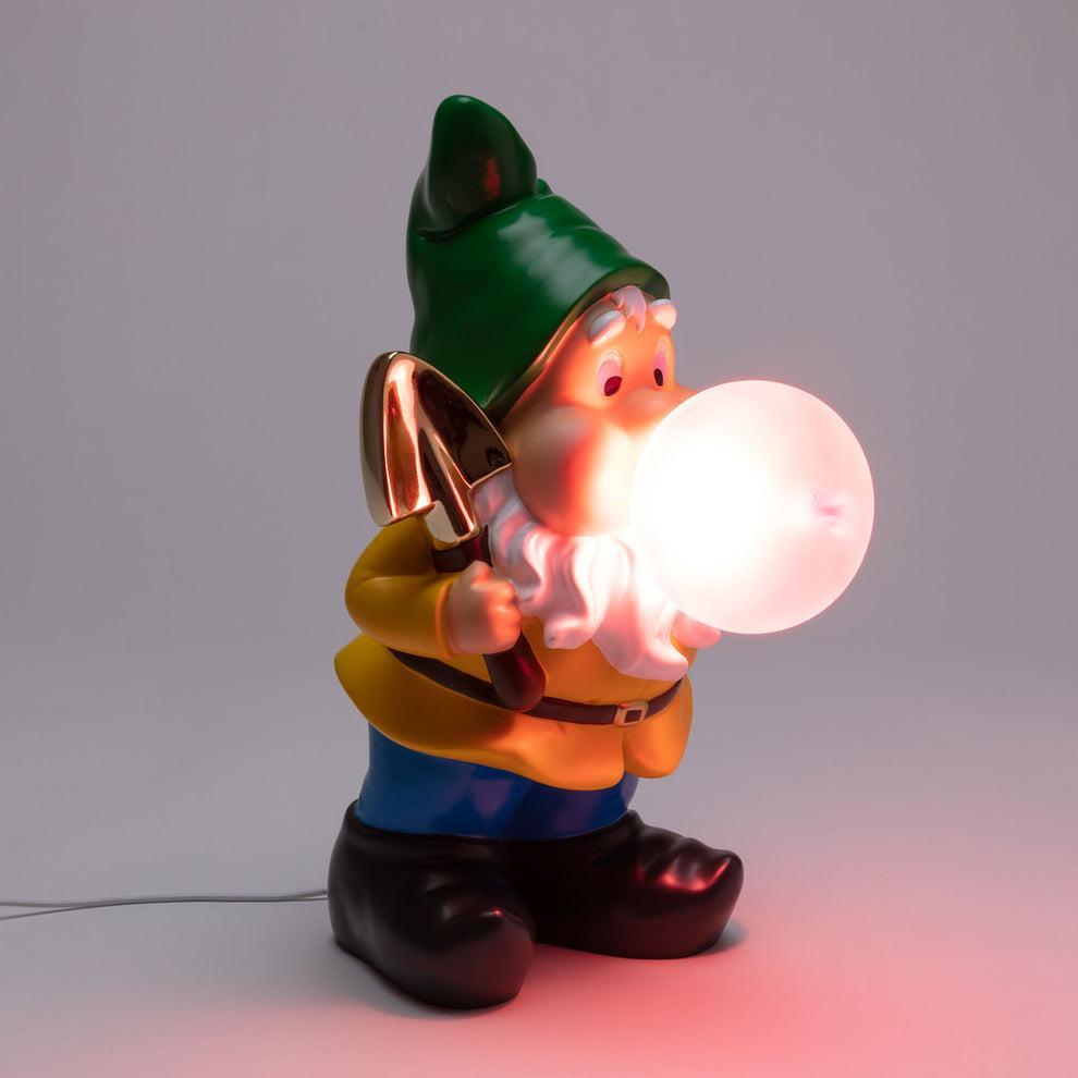 Lampada Seletti a forma di gnomo illuminata con bolla luminosa bianca su fondo grigio