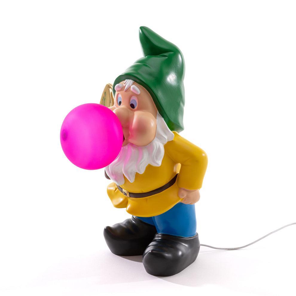 Lampada Seletti gnomo con pala dorata, cappello verde e bolla rosa vista laterale su fondo bianco