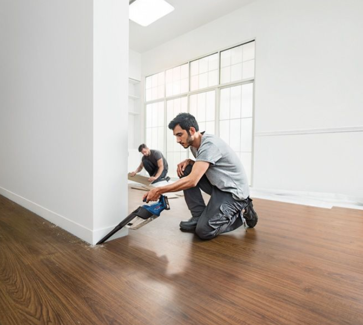 Artigiano che utilizza aspiratore portatile Bosch 18V su pavimento in cantiere