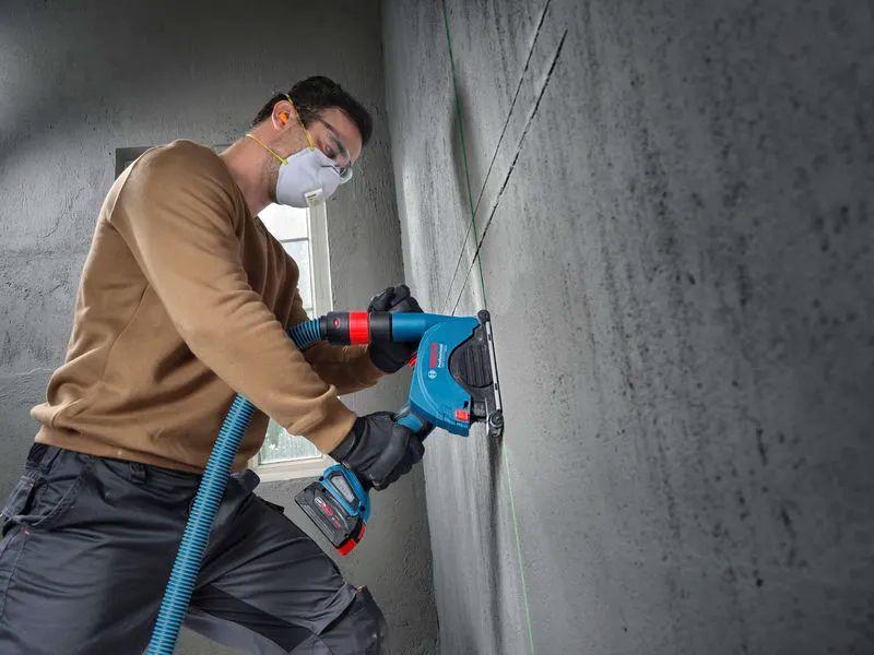 Operatore utilizza utensile Bosch professionale per lavorazione su muro in cantiere