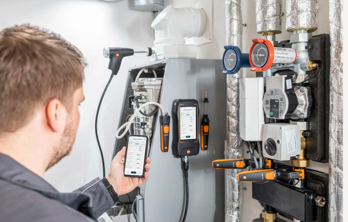 Tecnico utilizza analizzatore combustione Testo 320 su impianto HVAC con interfaccia mobile